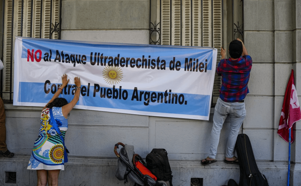 Activists in support of the national strike in Argentina against economic and labor reforms proposed by President Javier Milei, hang on the facade of the Argentine consulate, a banner with a message that reads in Spanish: “No to Milei’s far-right attack on the Argentine people”.